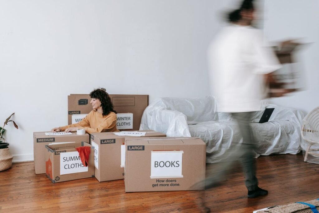 A couple packing labeled boxes in a minimalist living room, preparing for moving day.
